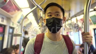 在地铁列车上，一名戴着黑色手术面罩的亚洲年轻人在新型冠状病毒Covid19号列车上关门